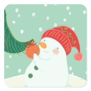 A snowman hanging an ornament on a tree square sticker
