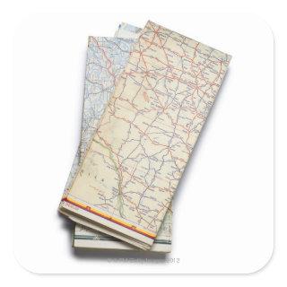 A stack of folded road maps on a white square sticker