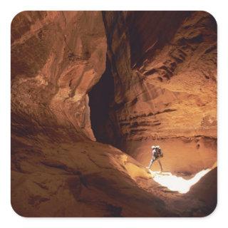 Canyoneer illuminated in the depths of a narrow square sticker