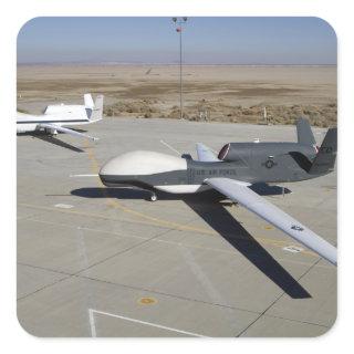 Two Global Hawks parked on a ramp Square Sticker