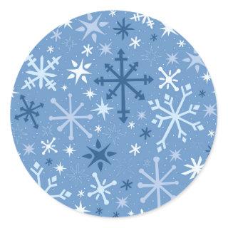 Whimsical flurry of blue snowflakes on sky blue classic round sticker
